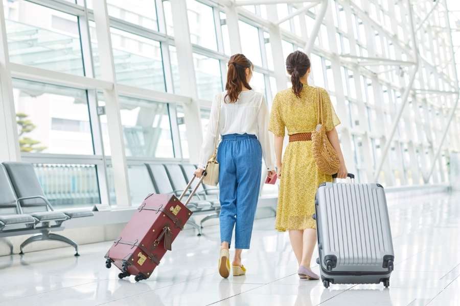 Deux voyageuses marchent avec leurs valises dans l'aérogare pour une assurance voyage internationale.